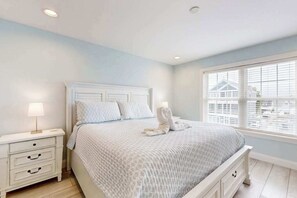 A bedroom with a bed, nightstands, a window, and a view of buildings. - Spacious home w/community boat launch, dock, patio, W/D, & AC (Selbyville)