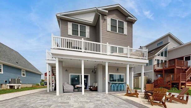 A two-story house with a balcony, a covered patio area, and outdoor seating. - Spacious home w/community boat launch, dock, patio, W/D, & AC (Selbyville)