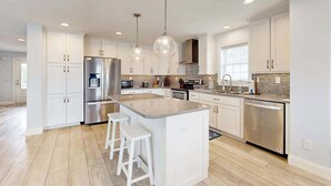 A modern kitchen with white cabinets, stainless steel appliances, and a central island with bar stools. - Spacious home w/community boat launch, dock, patio, W/D, & AC (Selbyville)