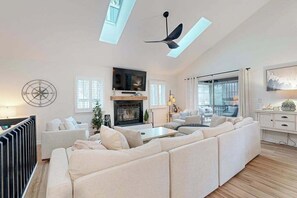A spacious living room with a fireplace, a large sofa, a TV, and a ceiling fan. - Town of South Bethany house w/patio, balcony, grill, near the ocean (Bethany Beach)