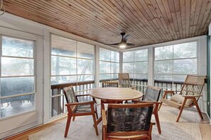 A sunroom with a wooden ceiling, large windows, a round table, and wicker chairs. - Town of South Bethany house w/patio, balcony, grill, near the ocean (Bethany Beach)