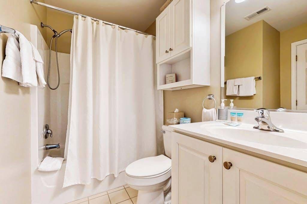 Un baño con ducha, inodoro, lavabo y armarios.