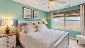 Een slaapkamer met een bed, twee bedlampen, een plafondventilator en een raam met uitzicht.
