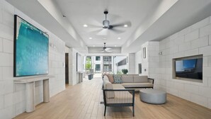 A spacious living area with a large TV, a ceiling fan, and a sofa. - 12min DT 6min Domain Studio-pool Free Parking (Austin)