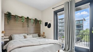 A bedroom with a bed, a window with curtains, a balcony, and a wall-mounted plant. - 12min DT 6min Domain Studio-pool Free Parking (Austin)