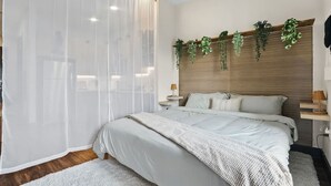 A bedroom with a bed, bedside tables, a wooden headboard, and hanging plants. - 12min DT 6min Domain Studio-pool Free Parking (Austin)