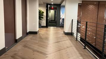 Un couloir doté d’un plancher en bois, d’une plante et d’une rambarde en métal.