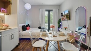 Una sala moderna con un sofá, una mesa de comedor, sillas y un televisor.