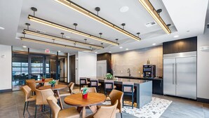 Una cocina moderna con electrodomésticos de acero inoxidable, un comedor con sillas de cuero y vistas a la ciudad a través de amplias ventanas.