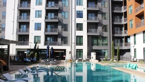 Ett modernt hotell med en swimmingpool, flera balkonger och ett välskött utomhusområde.