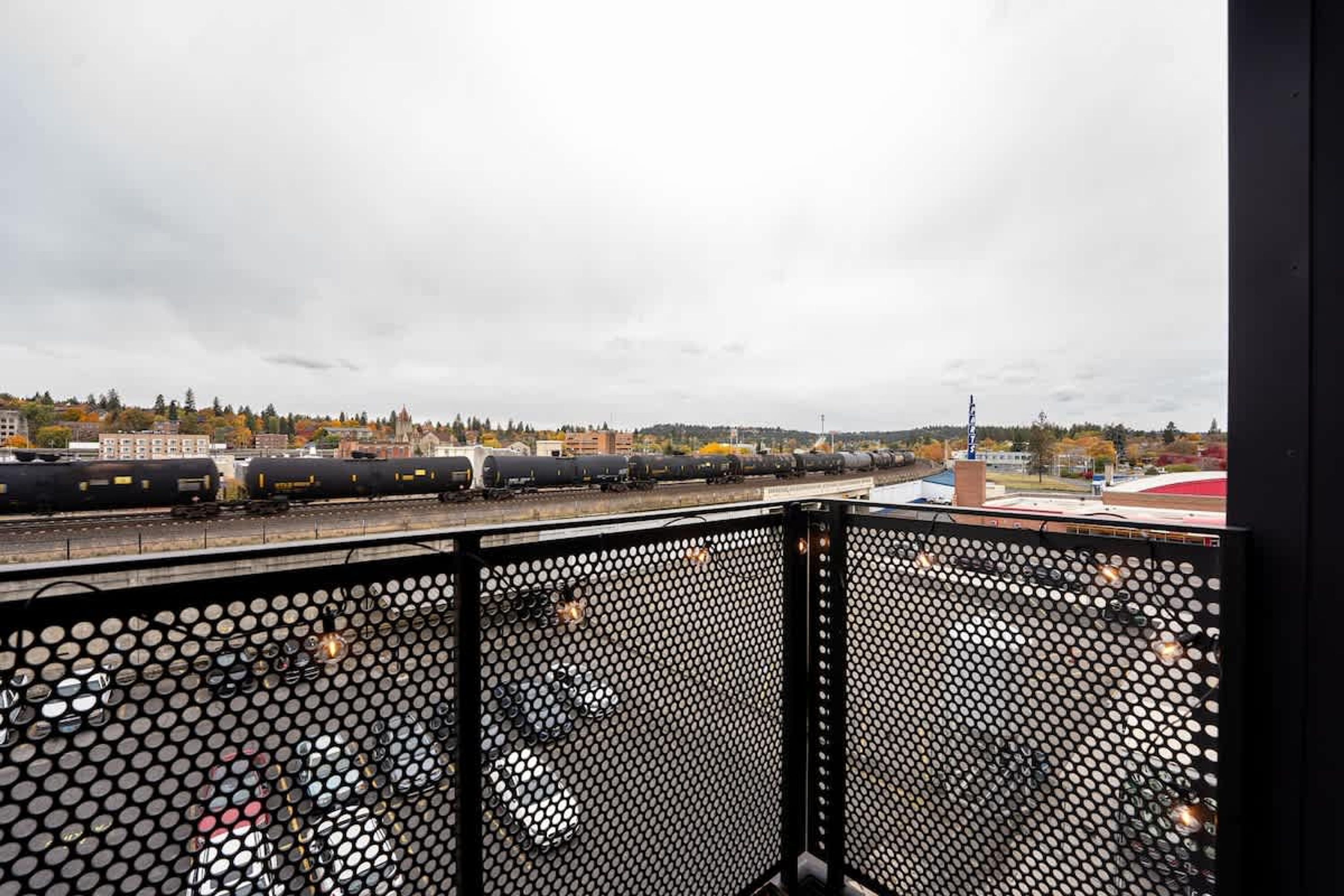 Ein Balkon mit Metallgeländer, der auf einen Bahnhof hinausblickt.