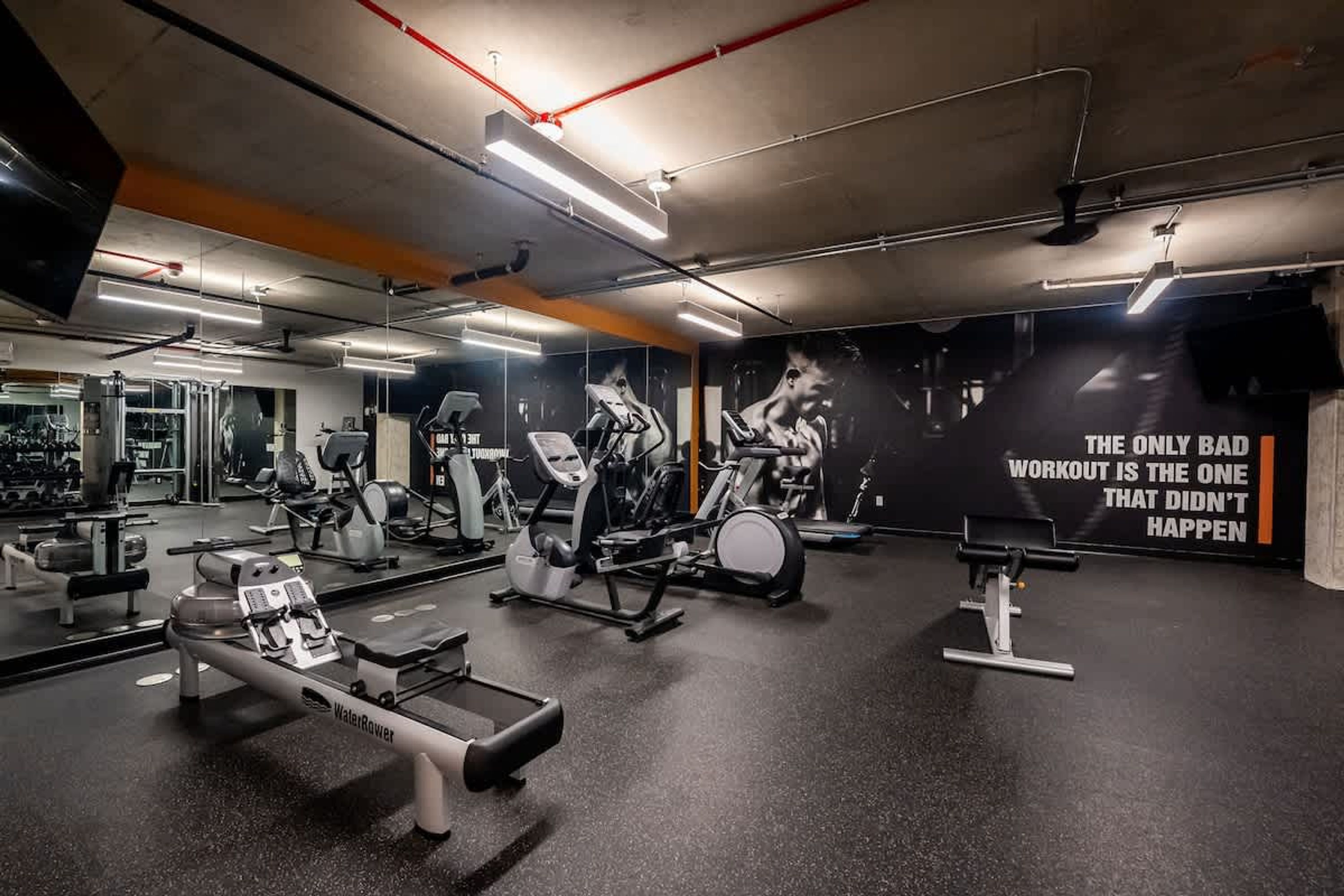 A gym with various exercise equipment, mirrors, and motivational posters.