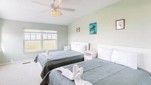 A hotel room with two beds, a ceiling fan, a window with blinds, and artwork on the walls. - Charming condo with nearby golf, outdoor pool & close to the beach (Ocean View)