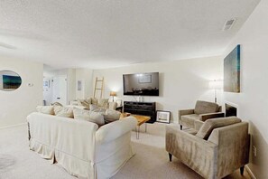 A living room with a sofa, armchairs, a TV, and a painting on the wall. - Westwood townhouse w/community pool, tennis court, bike to beach (Bethany Beach)