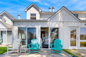 A white building with a covered patio area, two chairs, and a fan. - Mallard Lakes condo w/community pool, hot tub, tennis & basketball court (Selbyville)