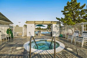 A hot tub area with a pergola, pool, and lounge chairs. - Mallard Lakes condo w/community pool, hot tub, tennis & basketball court (Selbyville)