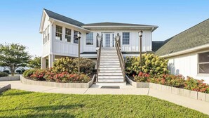 Ein zweistöckiges Haus mit Veranda, Treppe und einem gepflegten Garten.