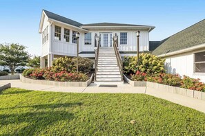 A two-story house with a front porch, a staircase, and a well-maintained garden.