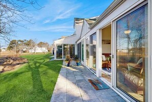 A modern house with large glass doors, a well-maintained lawn, and a clear sky.