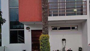 A modern two-story building with a balcony, large windows, and potted plants. - Casa Mariachi & World Cup (Las Víboras)