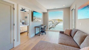 Habitación de hotel moderna con cama, escritorio y ventana grande que ofrece vistas de la ciudad.
