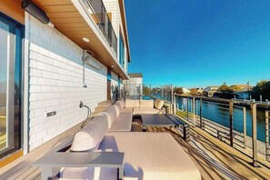 Eine Terrasse mit Sitzgelegenheit im Freien, einem Pool und Blick auf das Wasser.