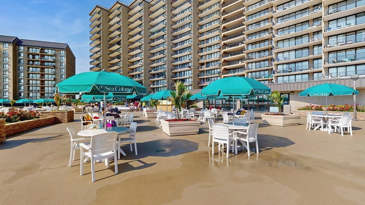 A hotel courtyard with outdoor seating, umbrellas, and a pool area.