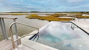 A swimming pool with a metal railing, surrounded by water and marshland. - Bayview Park bay front house w/private pool, amazing bay views, deck, balcony (Bethany Beach)