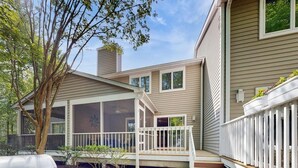 Une maison à deux étages avec un porche couvert, une terrasse clôturée et une cheminée.
