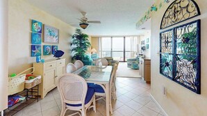 A dining area with a glass table, wicker chairs, and a ceiling fan. - Sea Colony oceanfront 7th-floor condo with pool & tennis/basketball courts (Bethany Beach)