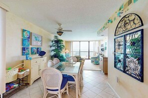 A dining area with a glass table, wicker chairs, and a ceiling fan. - Sea Colony oceanfront 7th-floor condo with pool & tennis/basketball courts (Bethany Beach)