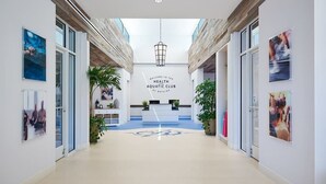 Moderni aula, jossa on vastaanottotiski, kyltti, jossa lukee: »Tervetuloa Health Aquatic Clubiin», ja lasiovet, jotka johtavat muihin tiloihin.