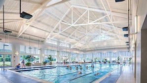 Una piscina interior con techos altos y ventanas amplias.