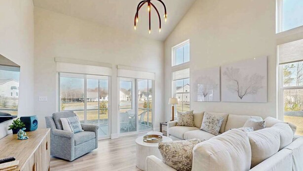A spacious living room with a large sofa, a smaller armchair, a coffee table, and a modern chandelier. - Milo's Haven townhouse w/community pool, grill, close to restaurants (Frankford)
