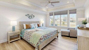 A bedroom with a large bed, a ceiling fan, a window with blinds, a nightstand, and a chair. - Milo's Haven townhouse w/community pool, grill, close to restaurants (Frankford)