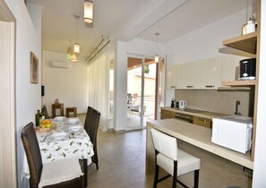 Eine kompakte Küche mit Essbereich, ausgestattet mit einem Tisch für vier Personen, einer Kaffeemaschine und einem Kühlschrank.