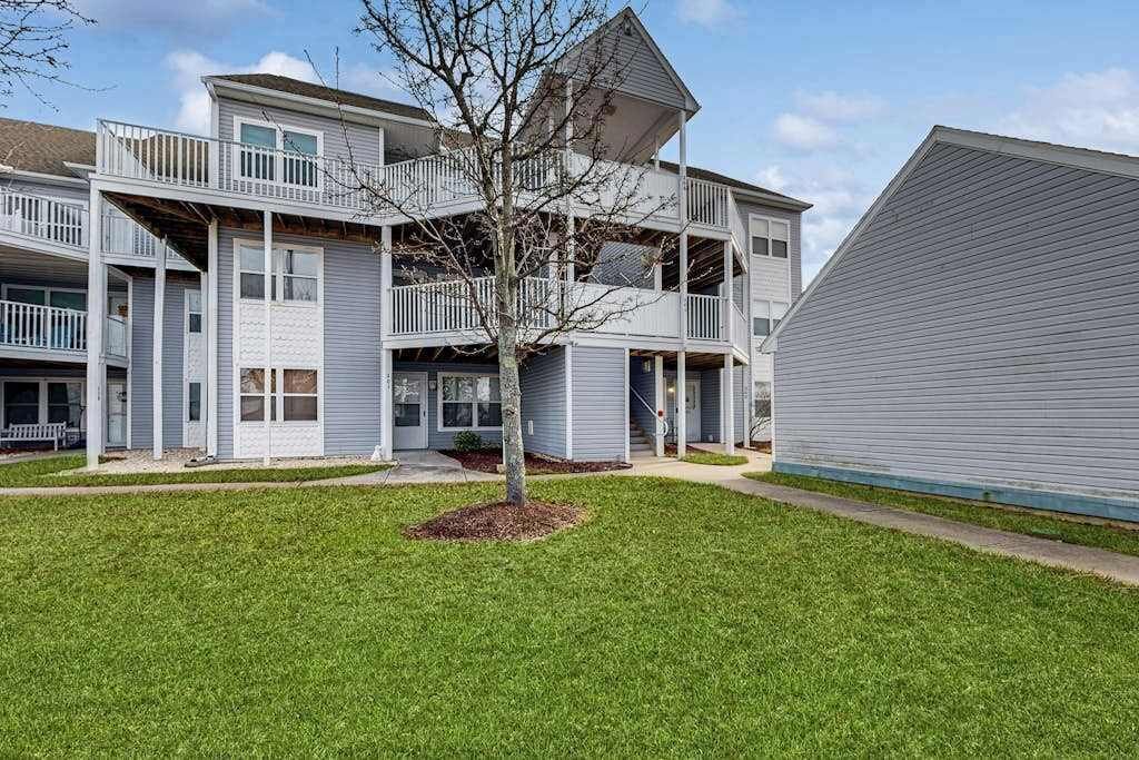 A multi-story residential building with balconies, a central courtyard, and a well-maintained lawn.