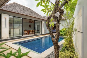 Una casa moderna con piscina, comedor y un amplio ventanal que da a una habitación.
