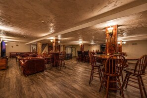Un'ampia stanza con pavimento in legno, un divano in pelle, sedie di legno e un tavolo da pranzo.