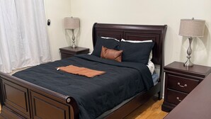A bedroom with a dark wooden bed, two bedside tables with lamps, a ceiling fan, and a wooden floor. - Charming 1-bedroom apartment with AC in lively Philadelphia / a beautiful view. (Philadelphia)