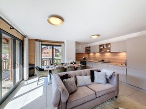 A modern kitchen with wooden cabinets, a dining area with a table and chairs, and a sofa with cushions. - Rennes - Apartment - Sleeps 6 - Jacuzzi (Les Gets)