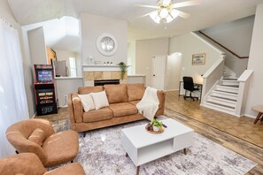 Ein Wohnzimmer mit braunem Sofa, weißem Couchtisch und einem Kamin.