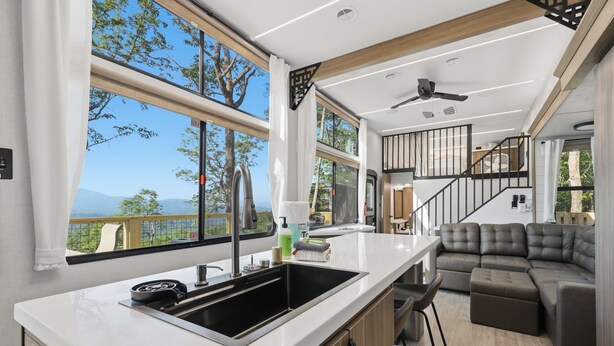 A modern kitchen with a large window, a built-in stove, and a sink. - The Pine- Smoky Mountains View Tiny House w/ Hot Tub & Deck (Tallassee)