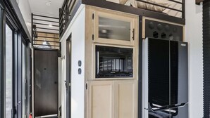 Eine kleine Küche mit einer eingebauten Mikrowelle, einem Kühlschrank und einem Holzkasten.
