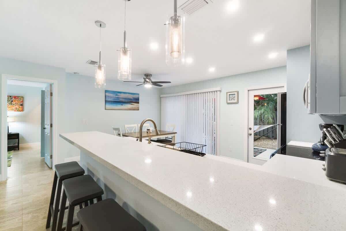 Uma cozinha moderna com uma ilha central grande, luminárias pendentes e ventilador de teto.