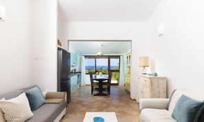 Ein Wohnzimmer mit einer Couch, einem Couchtisch und Blick auf den Ozean durch ein großes Fenster.