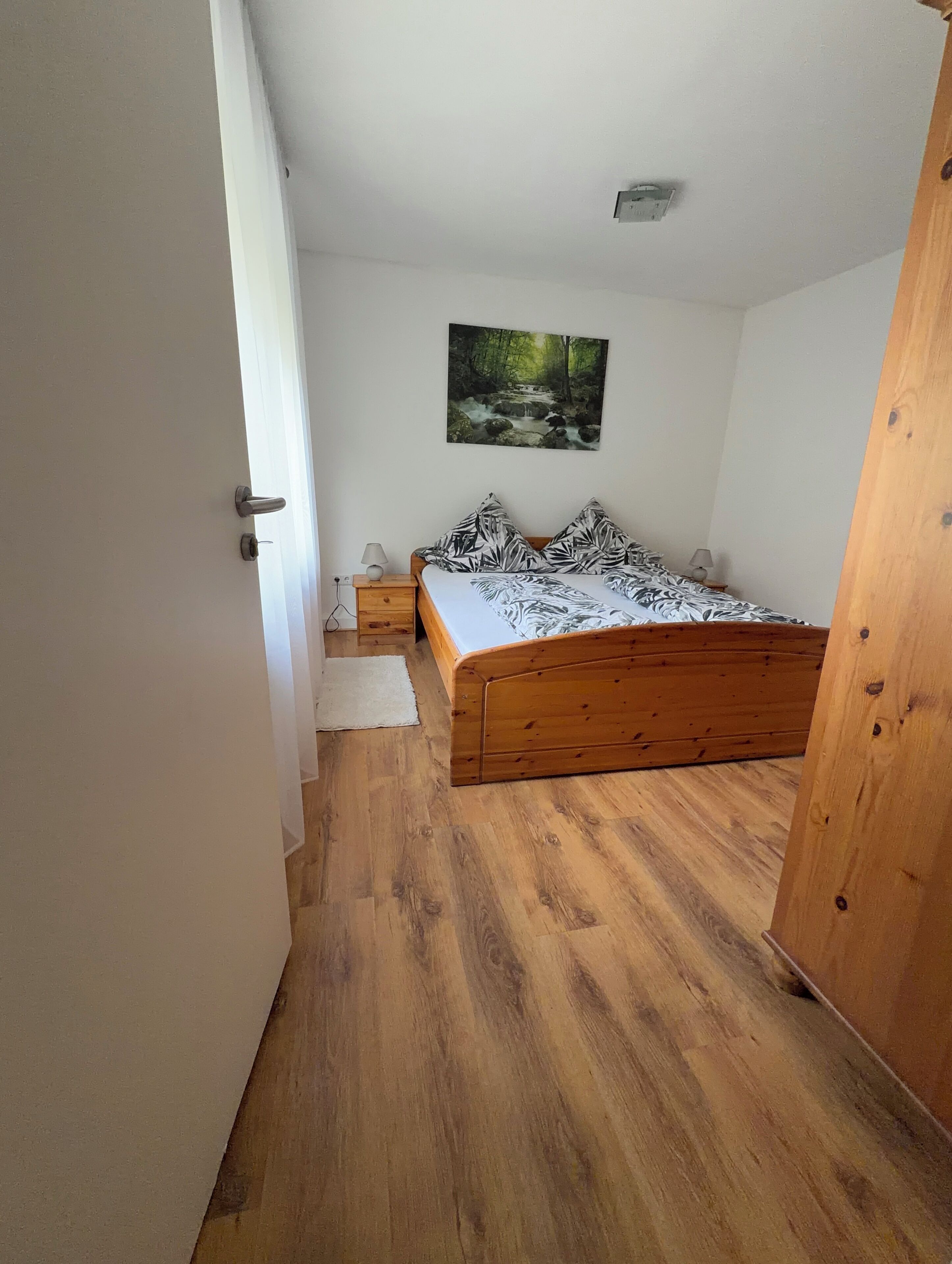 Une chambre à coucher avec un lit en bois, une table de chevet, une lampe et un tableau au mur.