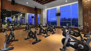 A gym with stationary bikes, large windows, and a wooden ceiling.