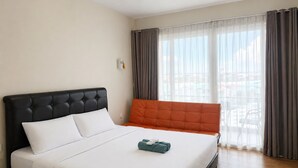 A hotel room with a bed, a window with curtains, and a view of buildings.