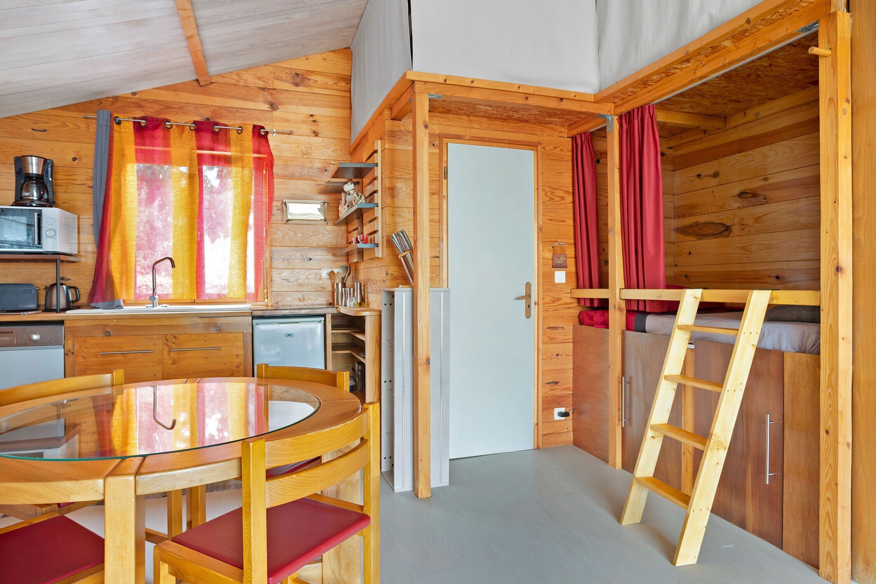 Eine kleine Küche mit Esstisch, Stühlen, Kühlschrank und Mikrowelle.